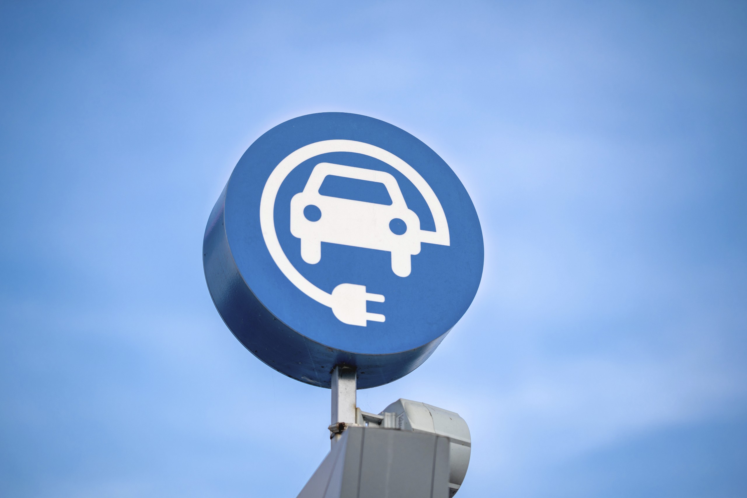 electric vehicle charging sign, blue sky background. Schild zum Laden von Elektrofahrzeugen, blauer Himmel im Hintergrund.